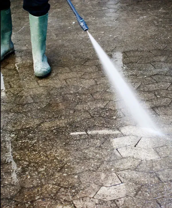 High-pressure water spray cleaning concrete driveway surface