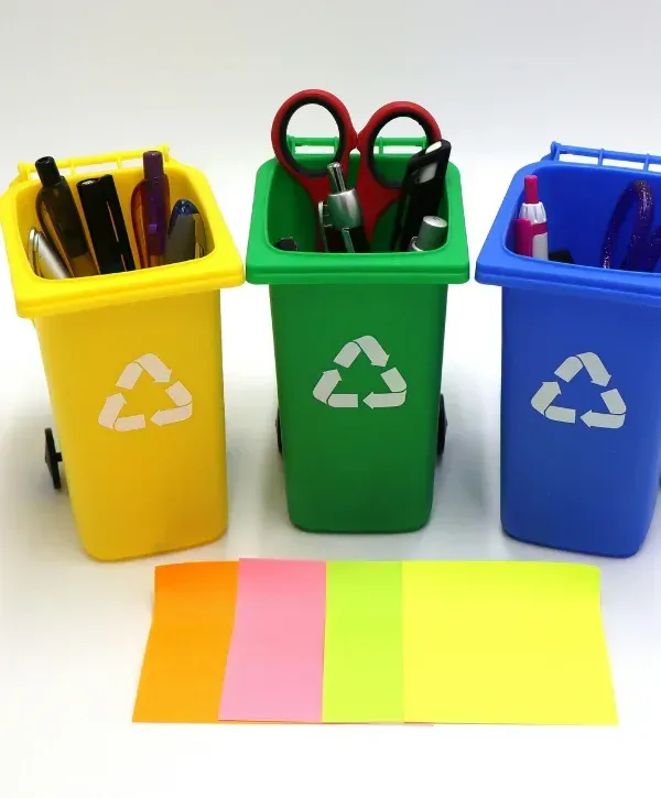 Mini colorful recycling bins holding office supplies and stationery.