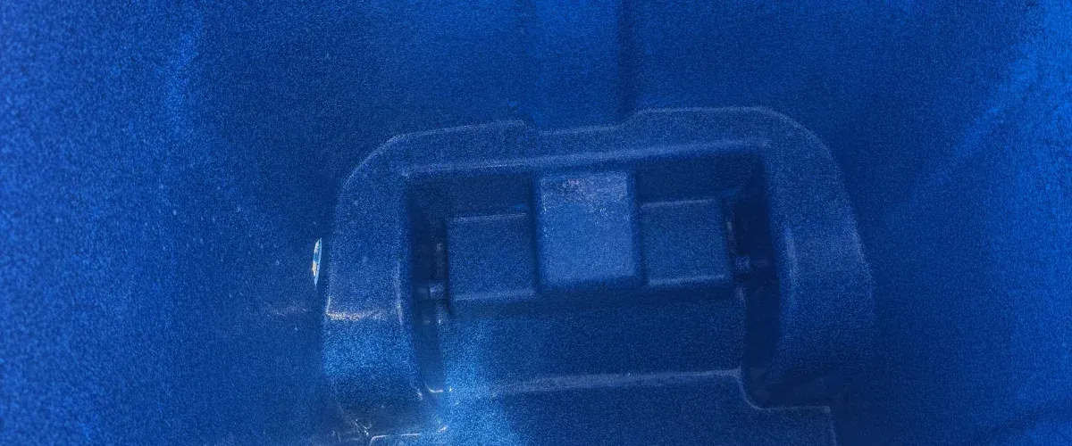 A close-up, high-angle view of the textured, deep blue plastic interior of a container with molded structural elements visible.