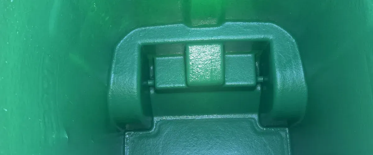 A close-up, top-down view of a textured, forest green plastic container interior with a prominent hinge mechanism.