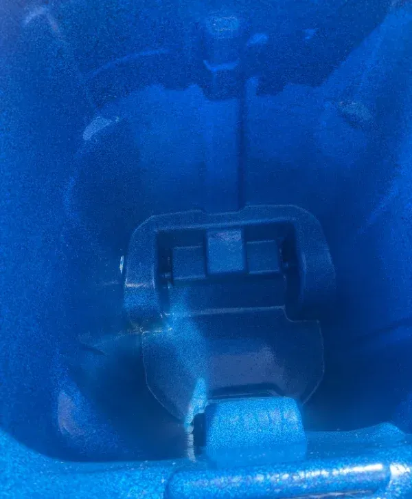 A close-up, top-down view of a deep blue textured plastic interior with a raised, rectangular, darker blue mechanism.