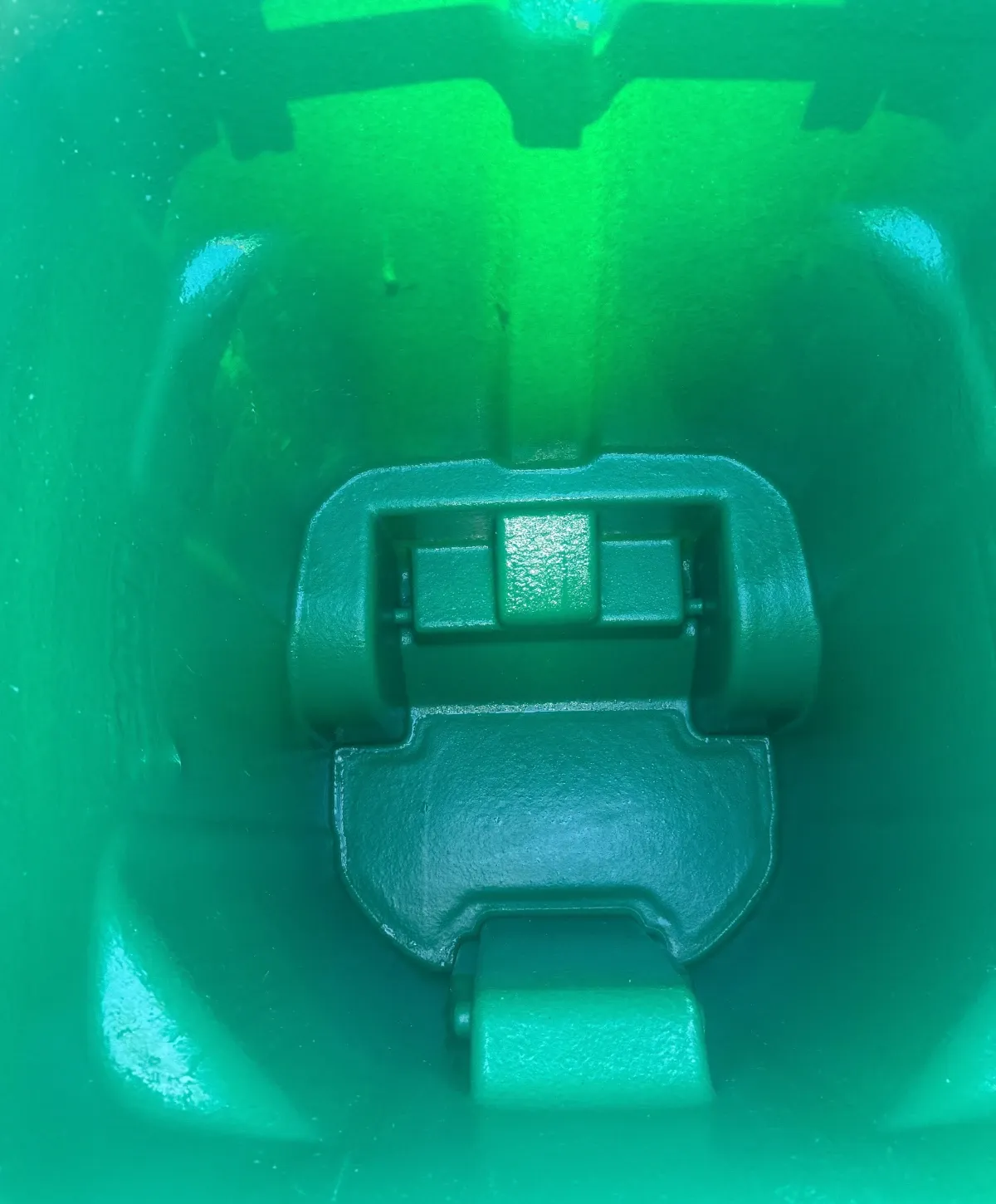 A close-up, top-down view inside a bright green plastic container, showing molded textures and a dark green latch mechanism.