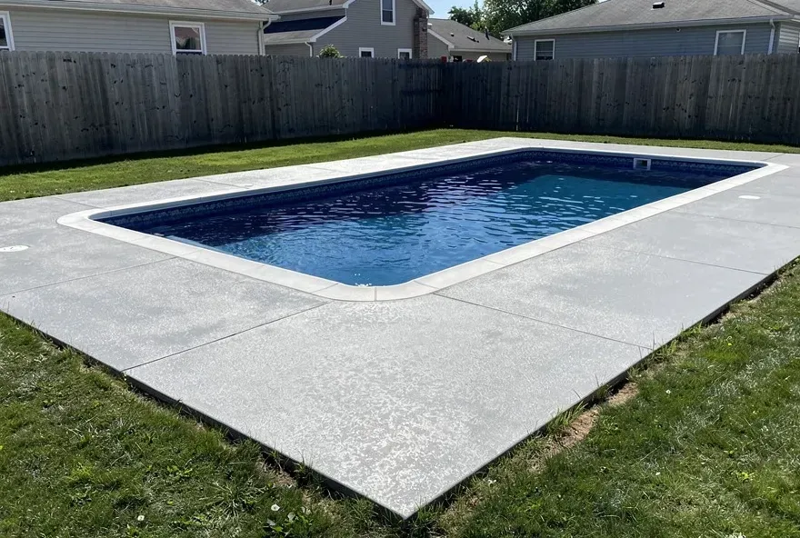 Freshly finished concrete pool deck surrounding a residential inground pool in North Tonawanda, New York