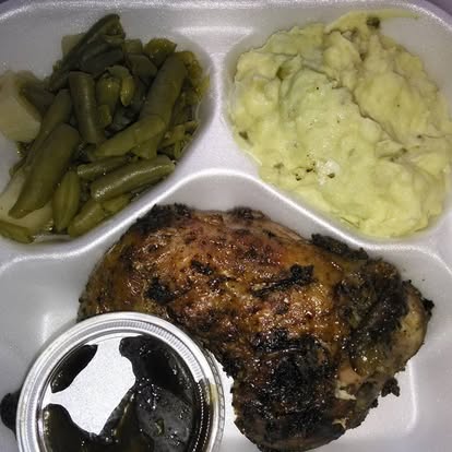 Close-up of a chargrilled burger with melted cheese, lettuce, tomato, and house sauce on a toasted bun, served on a wooden board.
