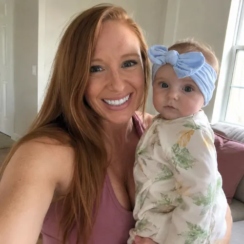 Crystal Pergola smiling in activewear holding her baby