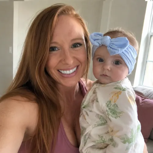 Crystal Pergola smiling in activewear holding her baby