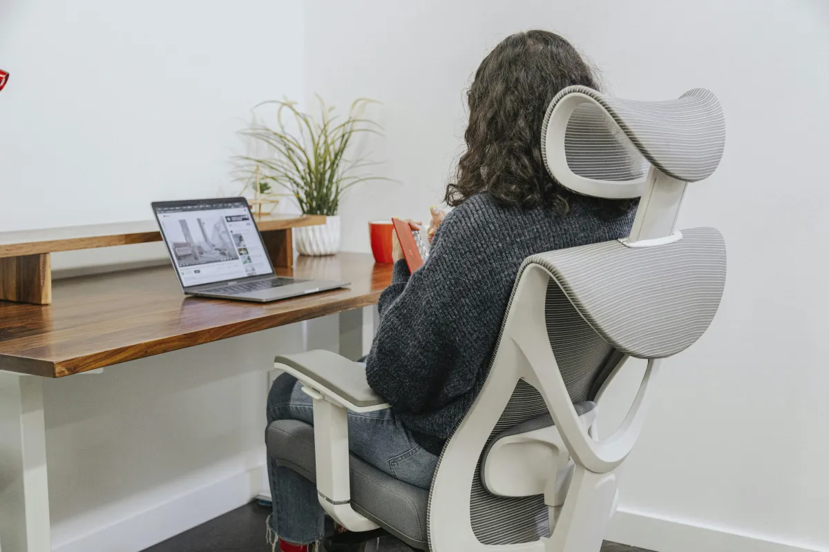 Person sitting at a desk in an ergonomic office chair, illustrating posture linked to lower back pain