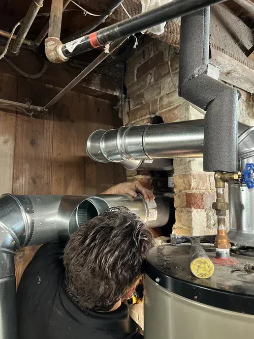 Technician fitting a metal chimney liner inside the flue