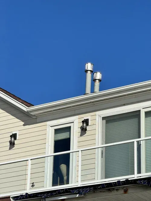 Technicians installing prefabricated metal chimney sections on a roof