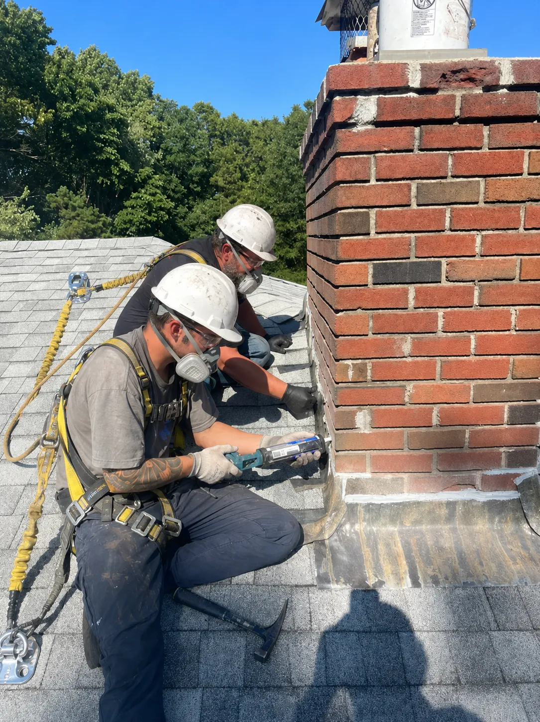 Mason applying waterproofing sealant to chimney masonry to prevent leaks