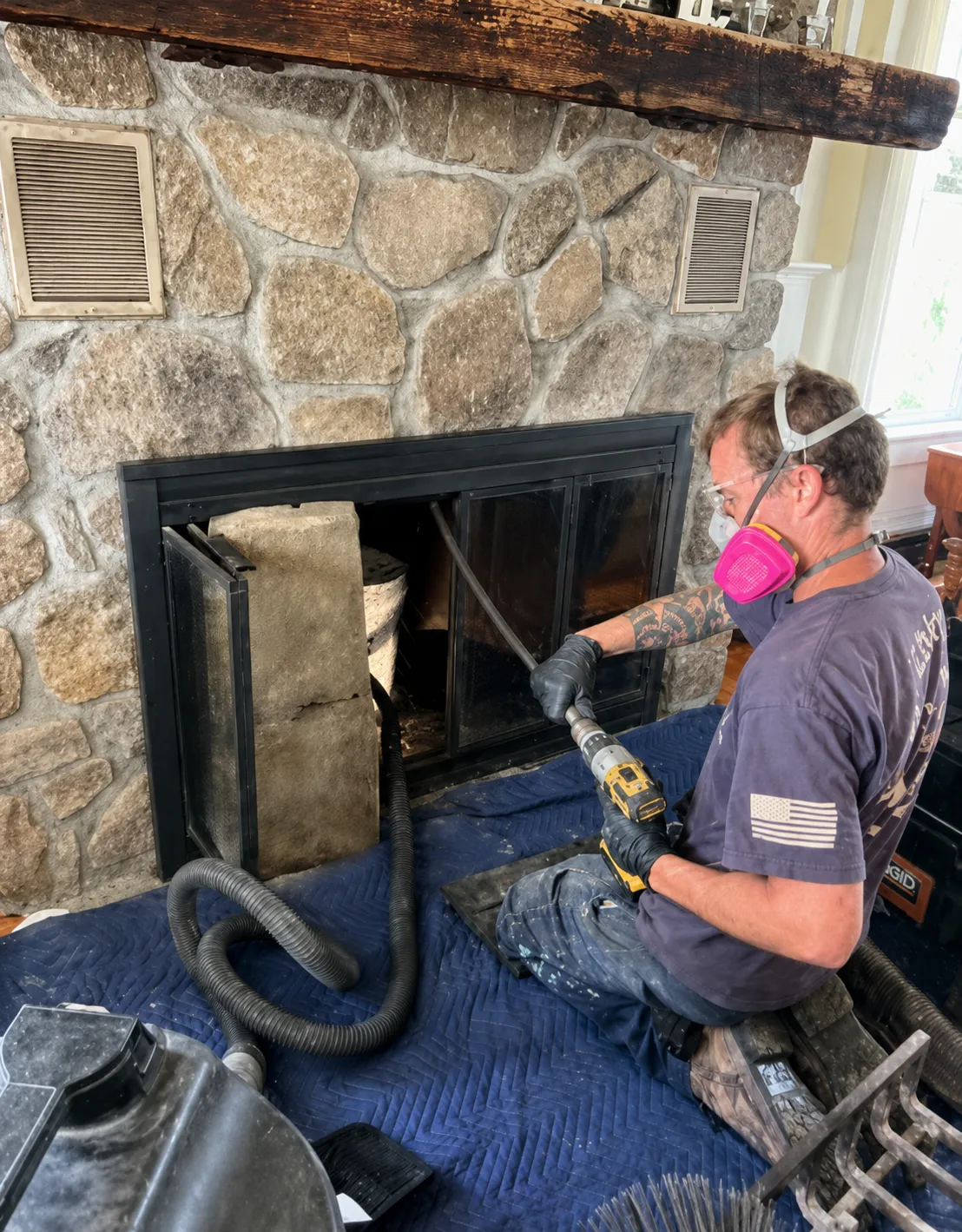 Technician performing a chimney sweep, removing soot with a rotating brush