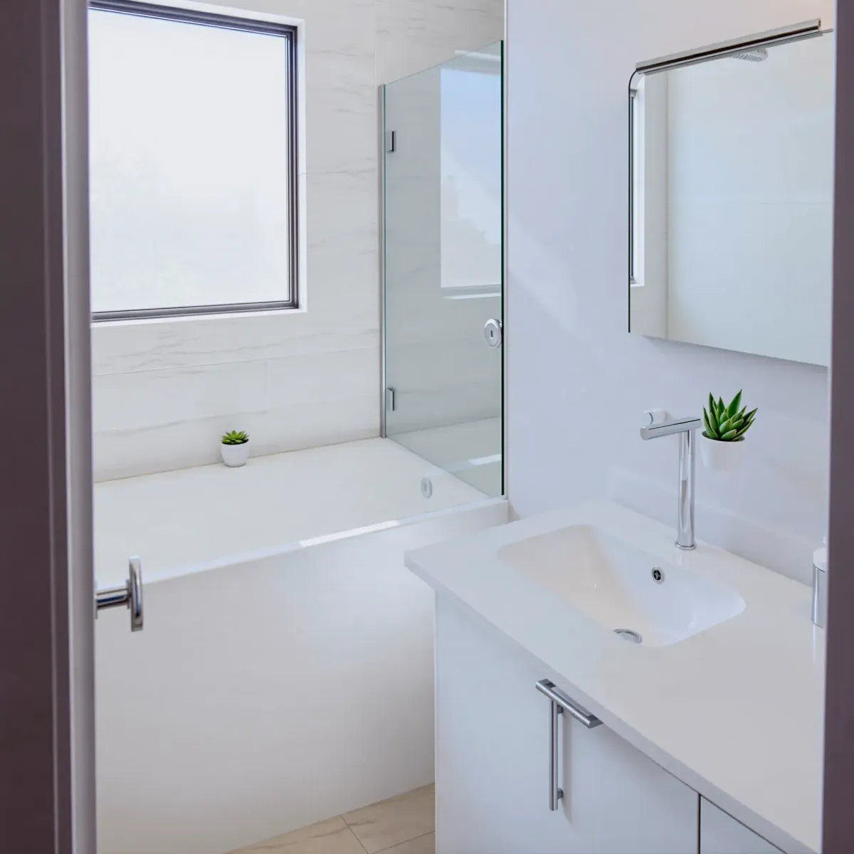 Remodeled small bathroom in Rancho Park, CA with white vanity, marble countertop, glass shower, and neutral-toned tiles.