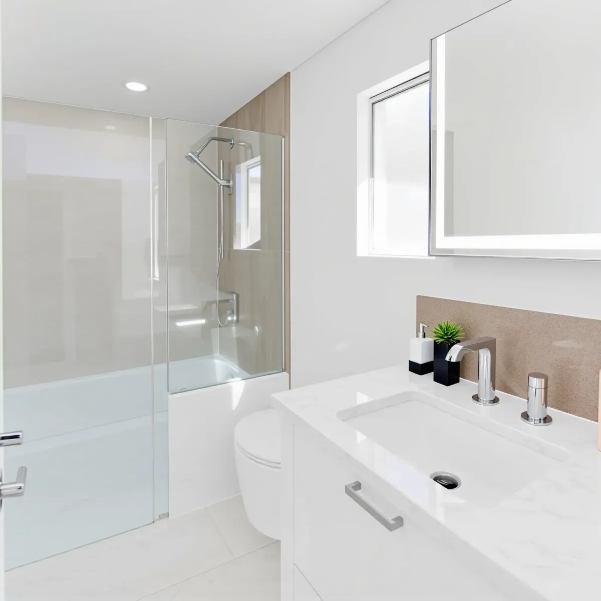 Recently renovated small bathroom in West LA featuring modern fixtures, marble countertops, glass shower, and bright natural light.