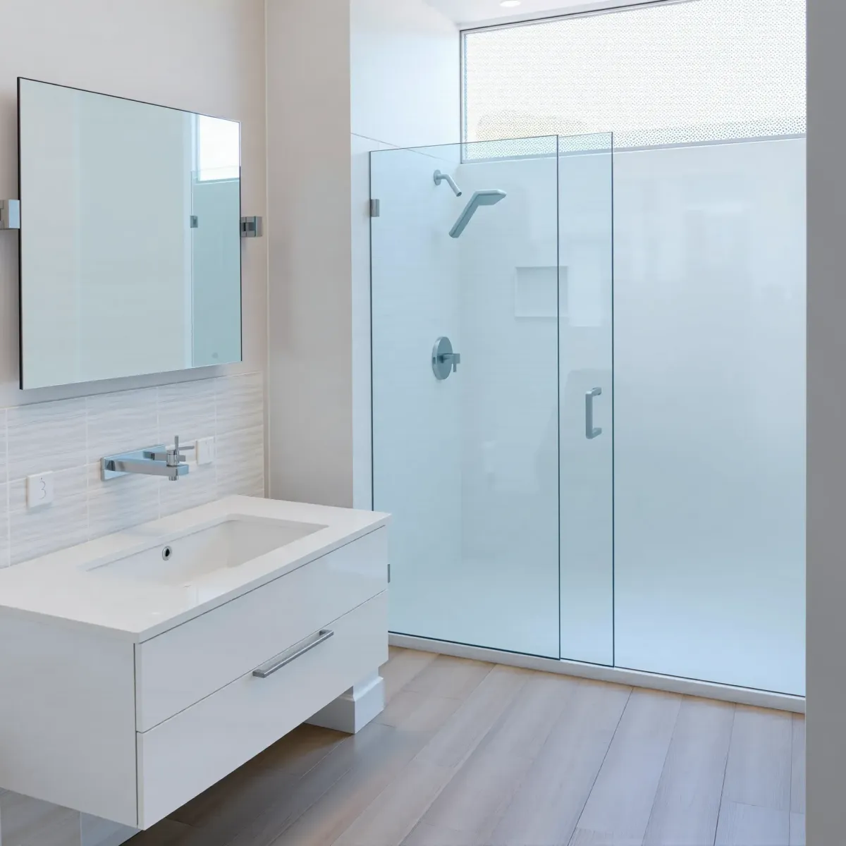 Recently renovated Century City bathroom with white vanity, glass shower, matte black fixtures, and natural light.