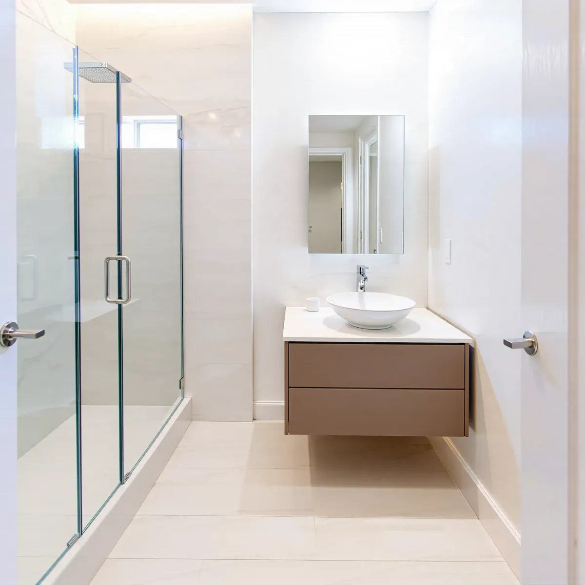 Modern small bathroom in Manhattan Beach, CA featuring sleek neutrals, floating vanity, glass shower, and contemporary decor.