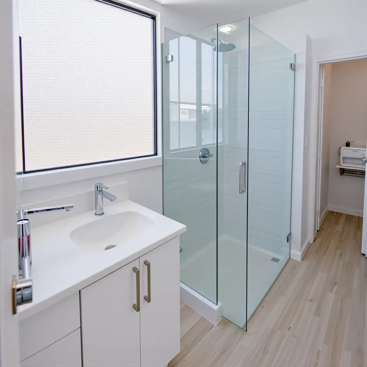 Small coastal bathroom remodel in Redondo Beach featuring subway tiles, seafoam walls, wood vanity, glass shower, and natural light.