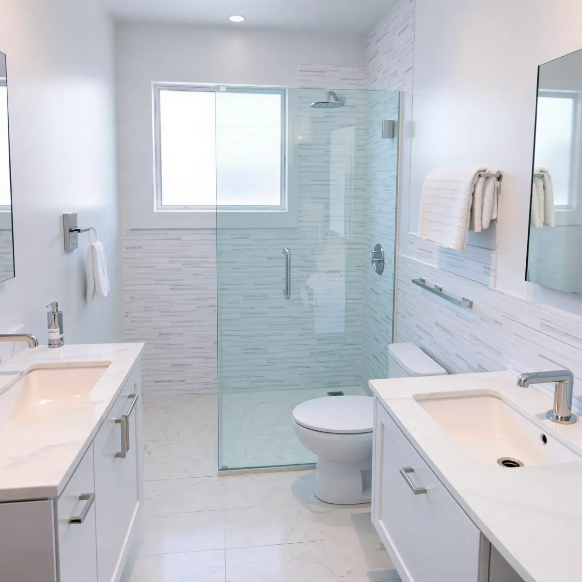 Modern small bathroom in Lomita, CA with white marble tiles, black hardware, wooden vanity, and glass shower.