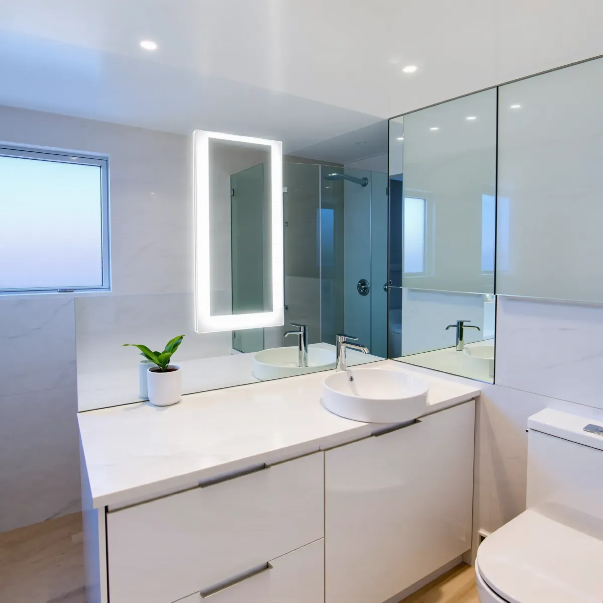 Remodeled small bathroom in Lomita, CA with white vanity, granite countertop, glass shower, modern fixtures, and natural lighting.