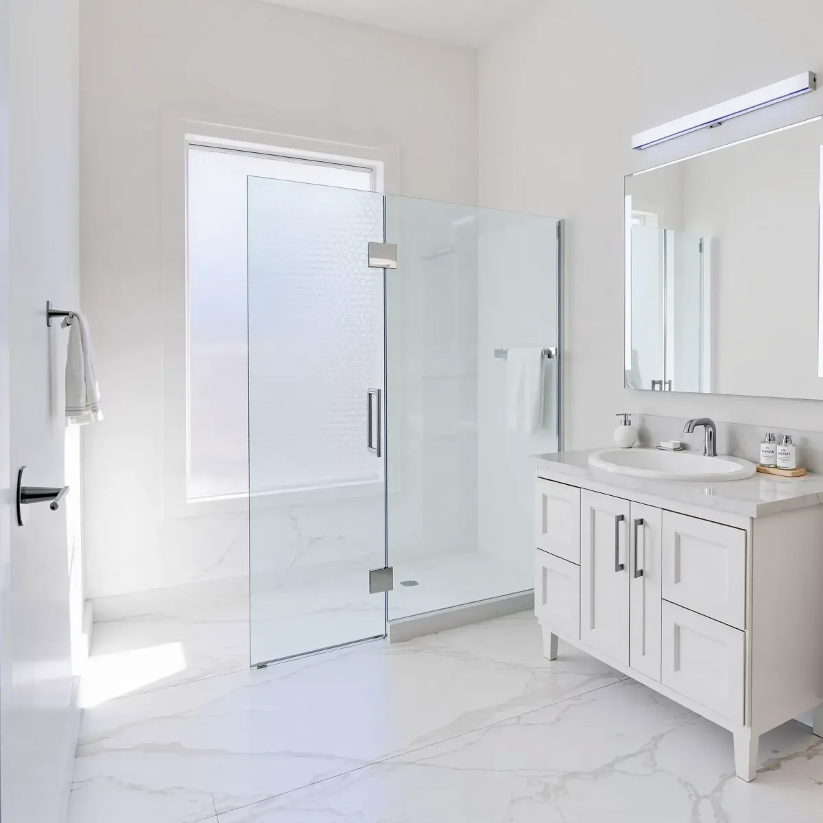 Modern small bathroom in Wilmington, CA featuring white subway tiles, a wood vanity, marble countertop, glass shower, and natural light.