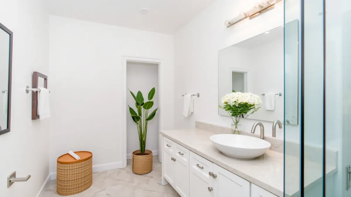 Remodeled Mar Vista bathroom with marble countertops, frameless glass shower, soaking tub, black fixtures, and natural light.
