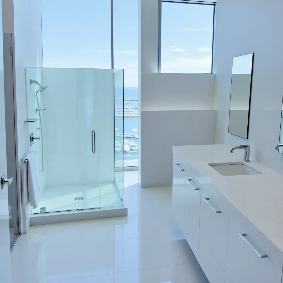 Elegant renovated bathroom in Marina del Rey with marble tiles, walk-in shower, freestanding tub, and coastal decor.
