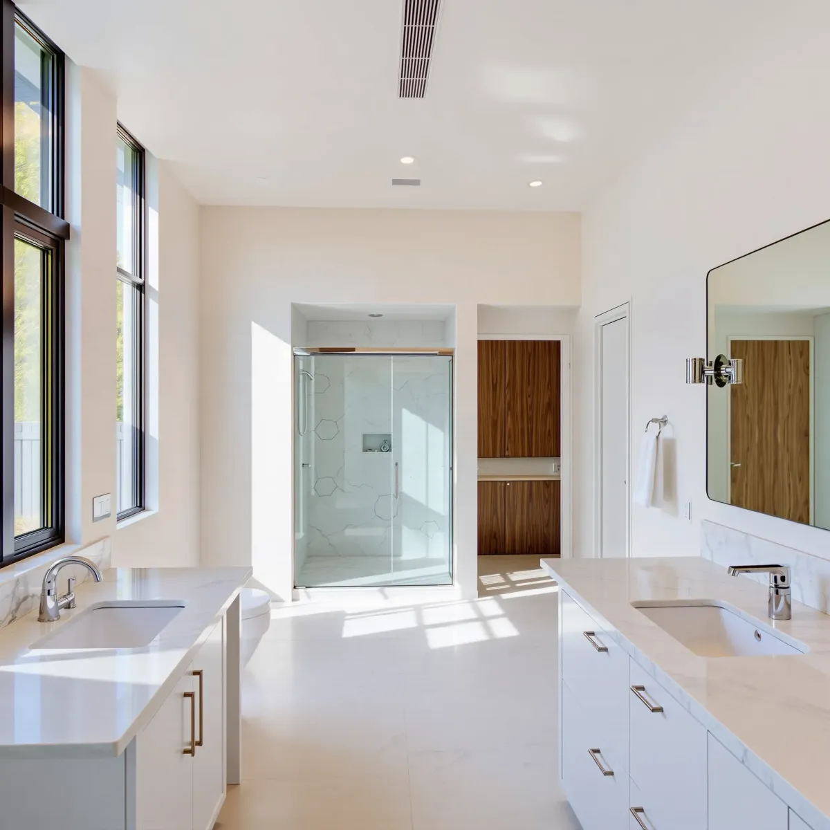 Modern remodeled LA bathroom with marble countertops, glass shower, sleek fixtures, natural light, and stylish decor.