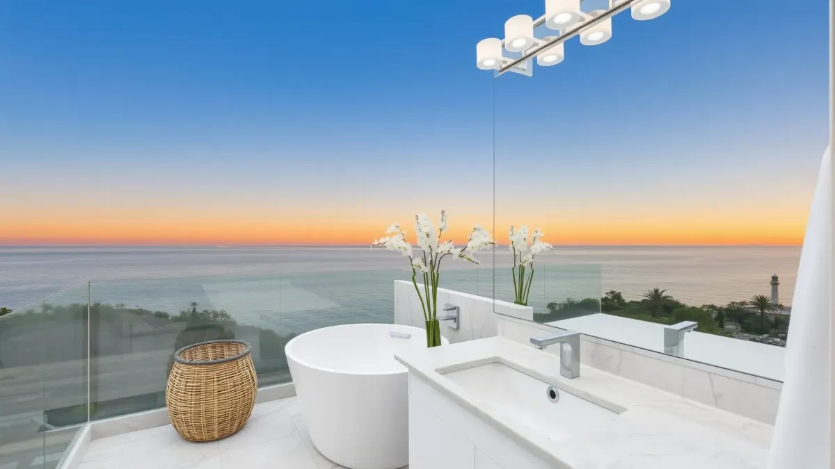 Remodeled Venice, CA bathroom with marble accents, a freestanding tub, walk-in shower, large frosted windows, lush outdoor view.