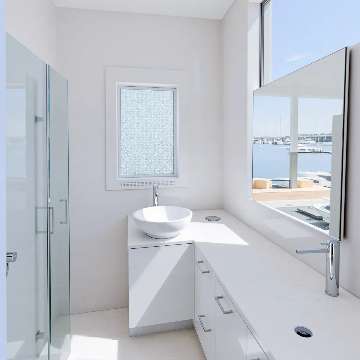 Renovated small bathroom in Marina del Rey with modern marble countertops, glass shower, floating vanity, and coastal decor.
