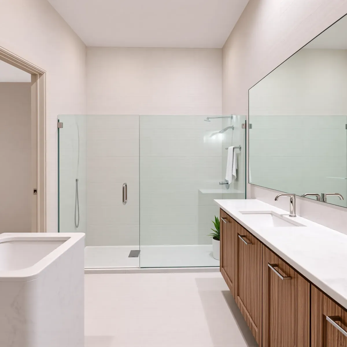 Renovated Hawthorne, CA bathroom with white marble countertops, glass shower, freestanding tub, and modern design details.