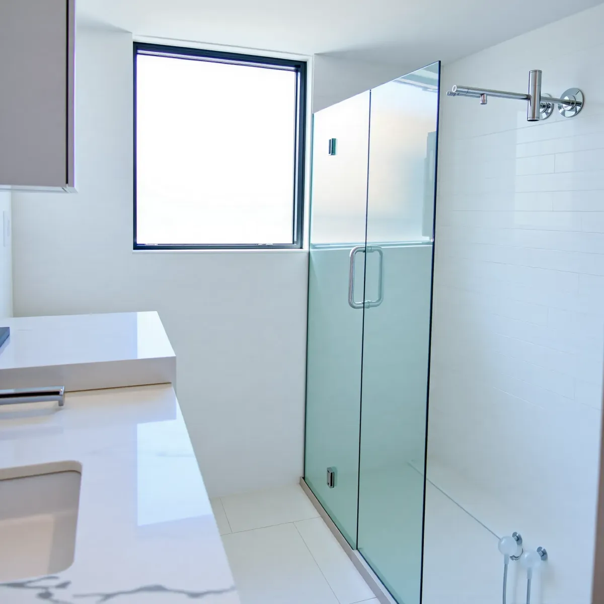 Bright, renovated Santa Monica bathroom with marble countertop, frameless shower, black mirror, coastal decor, and palm view.