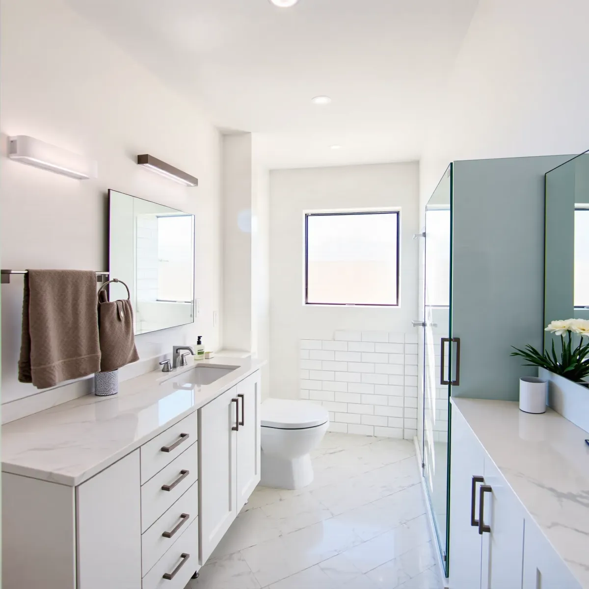 Small Wilmington, CA bathroom remodel with white marble tiles, glass shower, floating vanity, and coastal blue accents.