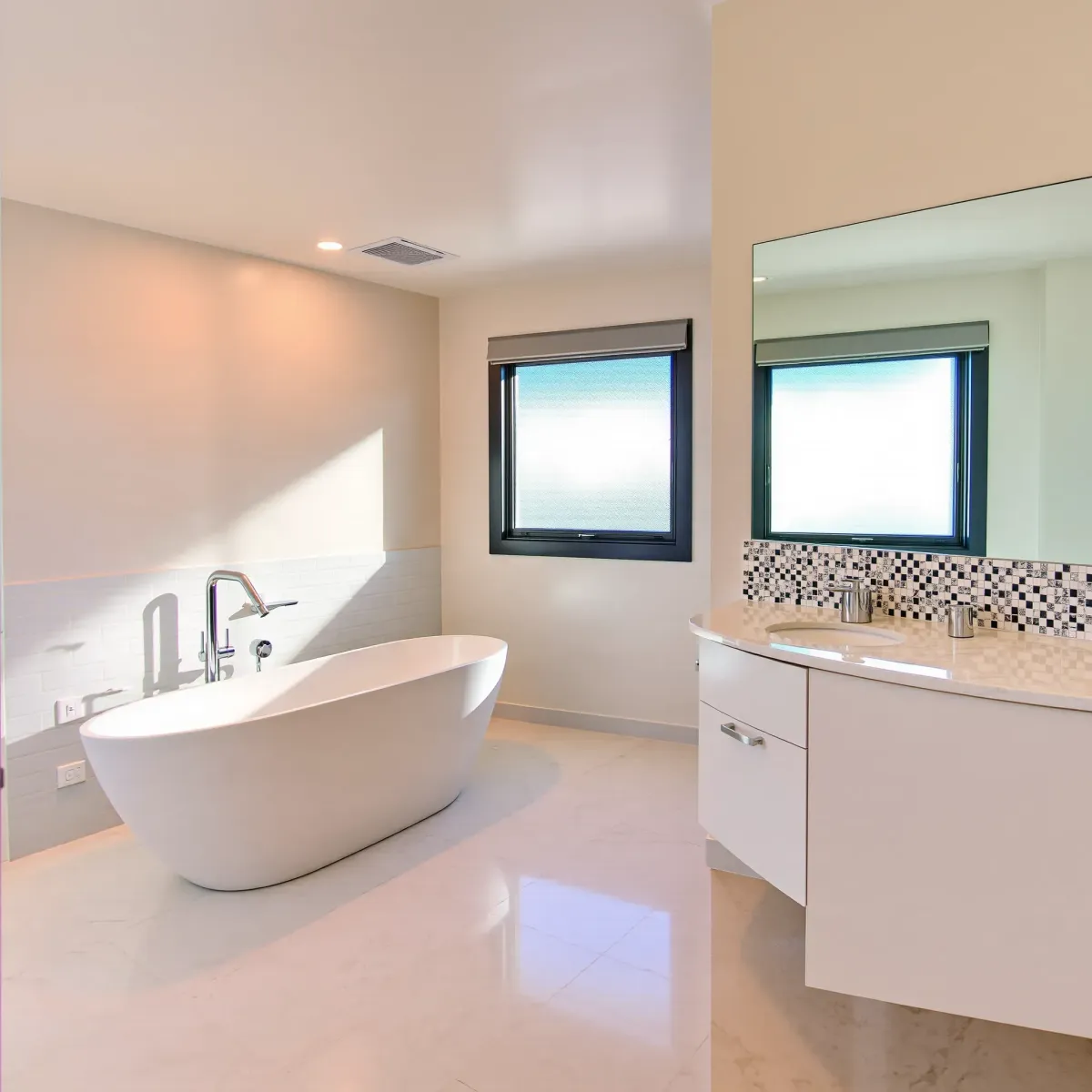 Modern Los Angeles bathroom with marble vanity, freestanding tub, subway tiles, and natural light.