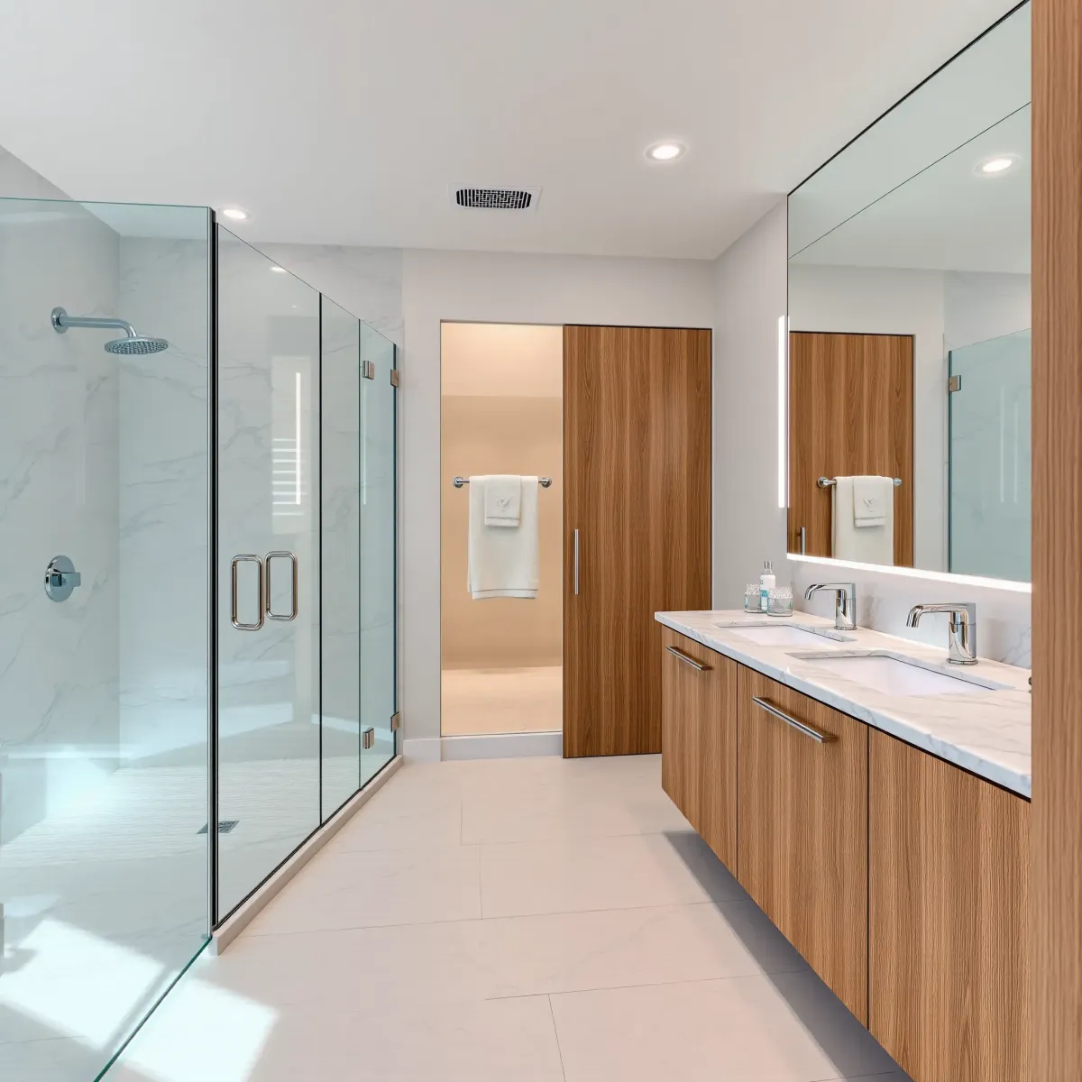 Modern Carson, CA bathroom with white tiles, marble accents, glass shower, bathtub, wooden vanity, and natural lighting.
