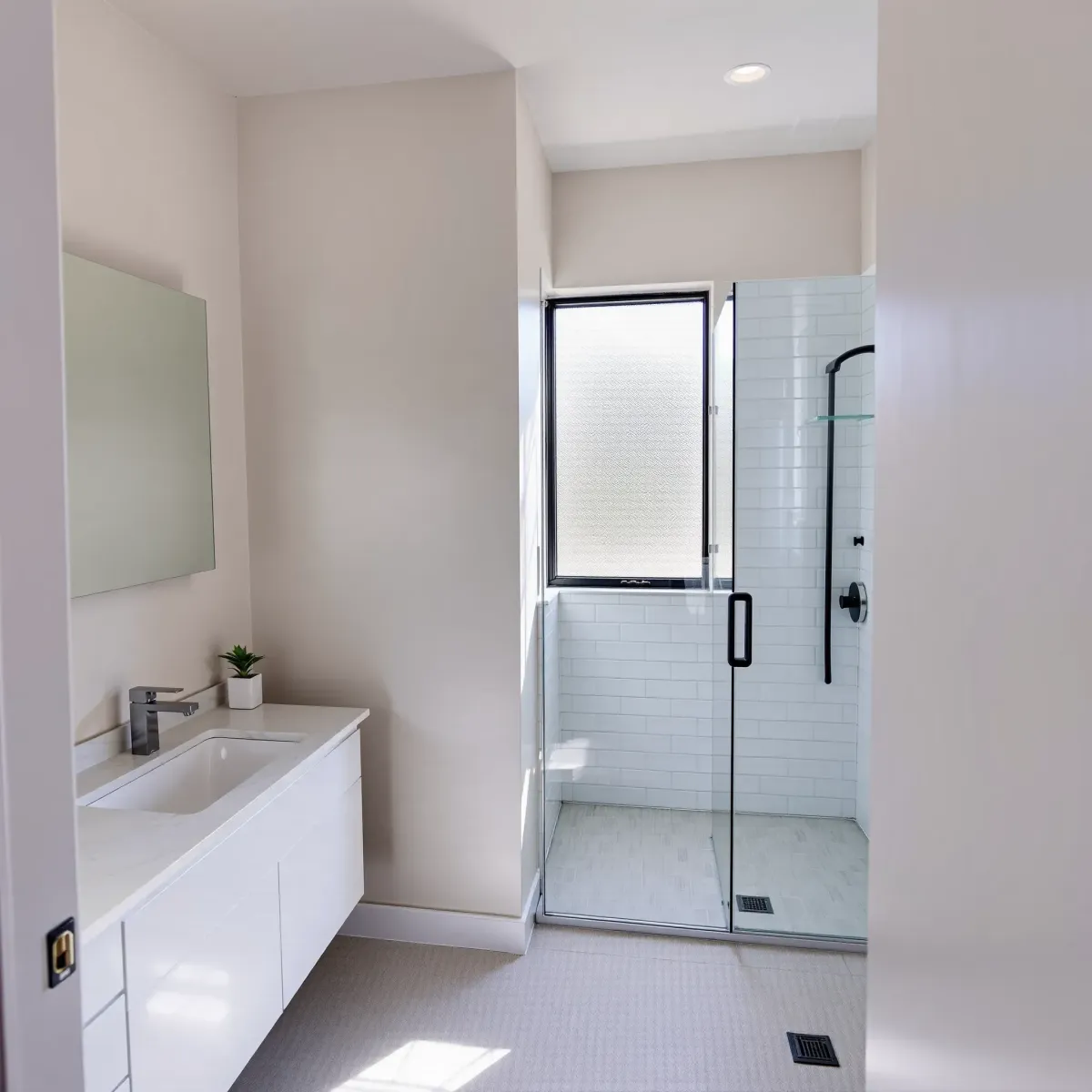 Modern small bathroom in Hyde Park, CA with a white vanity, glass shower, neutral colors, and sleek finishes.