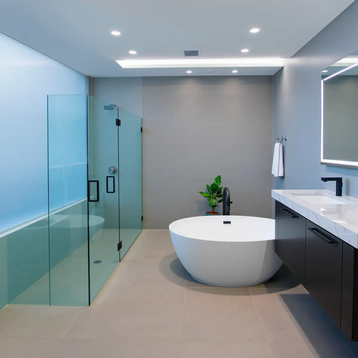 Modern South L.A. bathroom with walk-in glass shower, soaking tub, floating vanity, and sleek gray tiles.