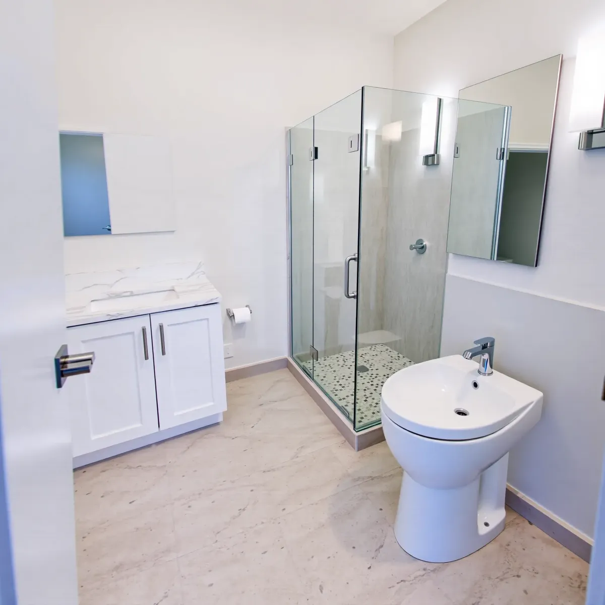 Small modern bathroom remodel in Carson, CA with white tile shower, wooden vanity, oval mirror, and remodeling tools.