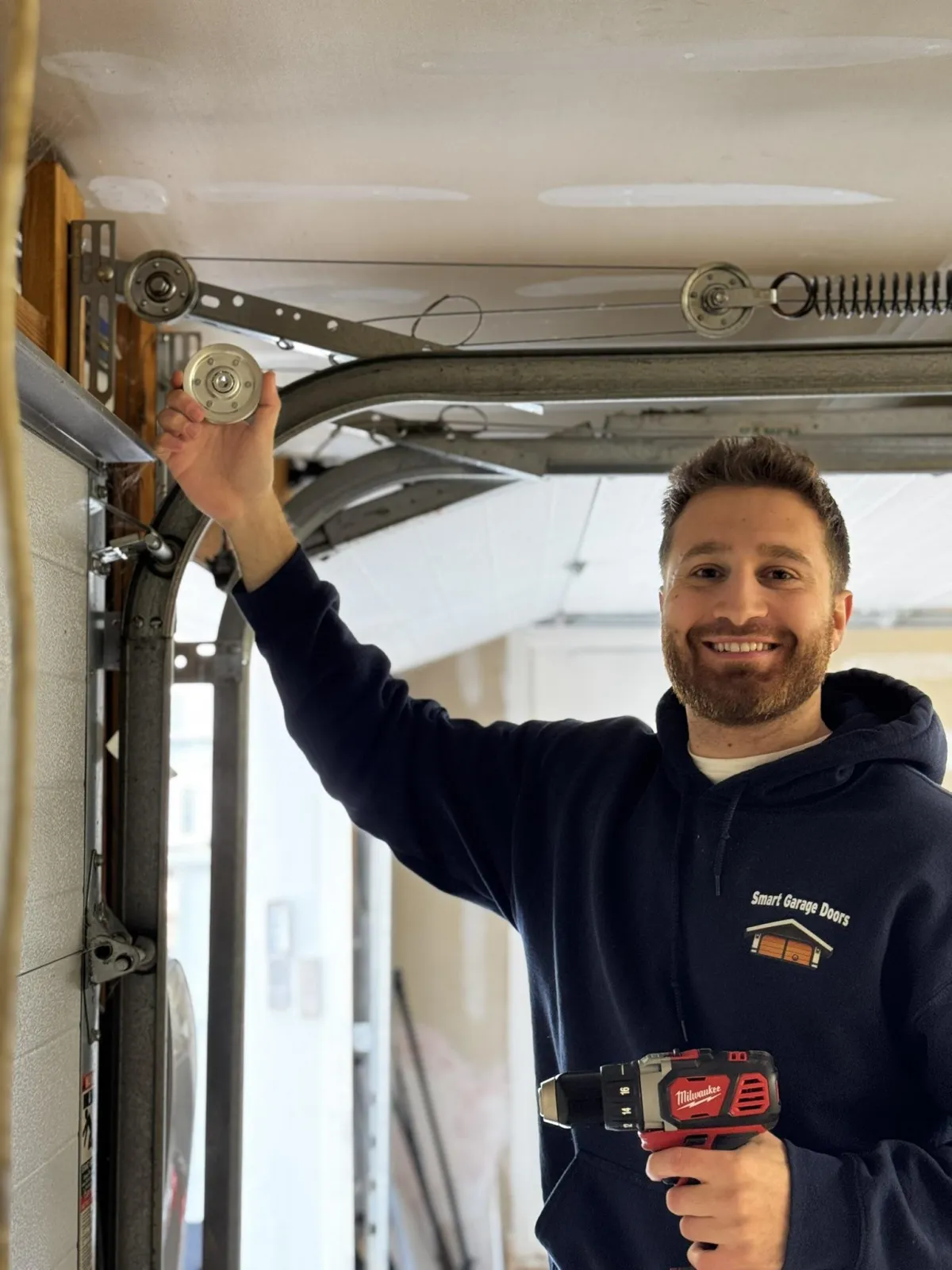 Garage door technician replacing pully repairing garage door