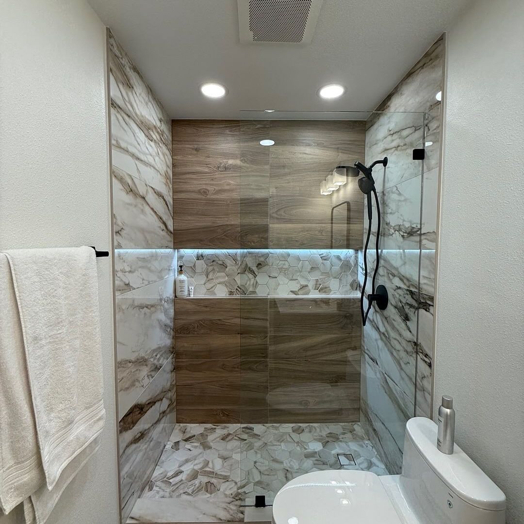 Custom walk-in shower with large-format tile walls, glass enclosure, and modern black fixtures
