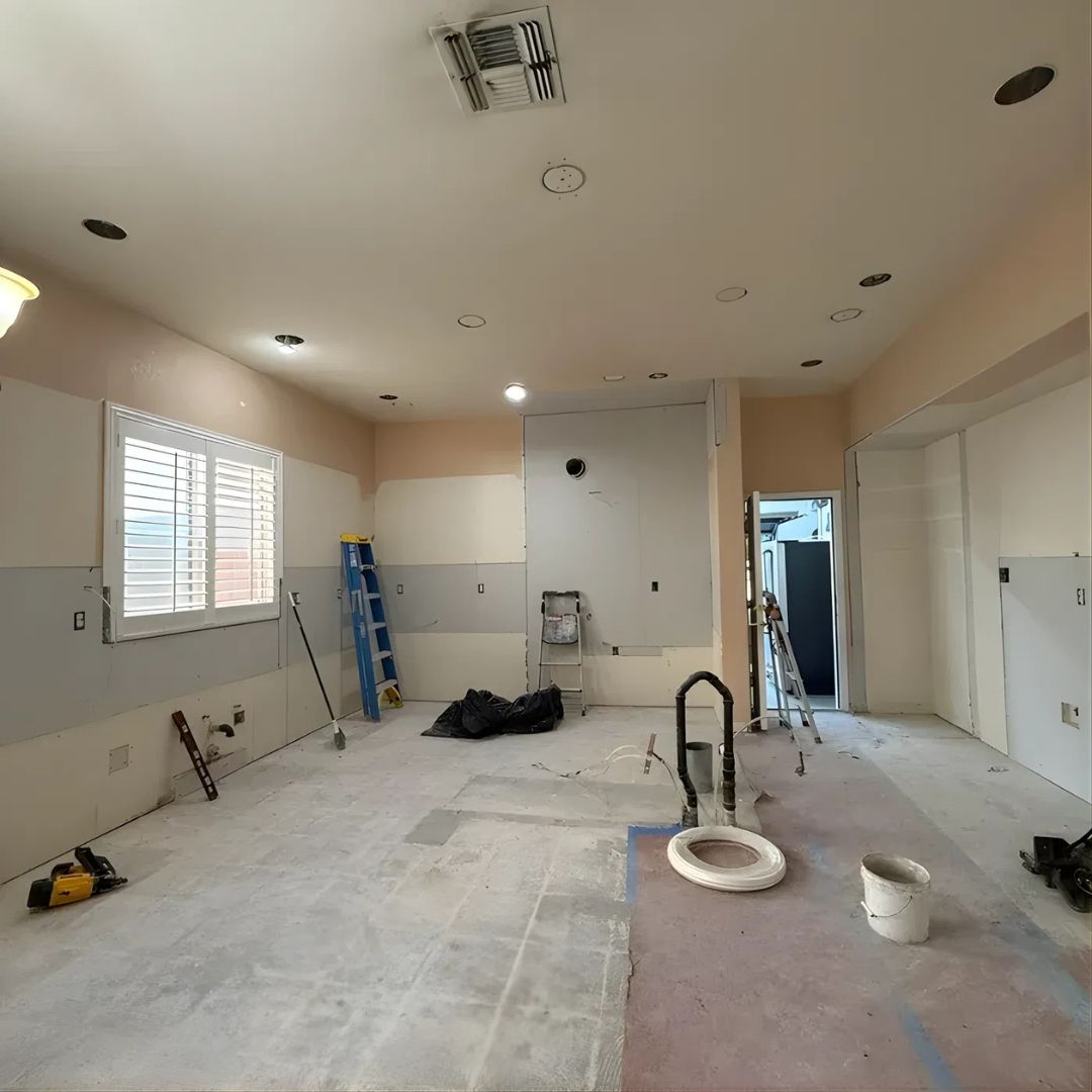 Kitchen before remodel with removed cabinets, exposed walls, unfinished flooring, and visible plumbing and electrical prep