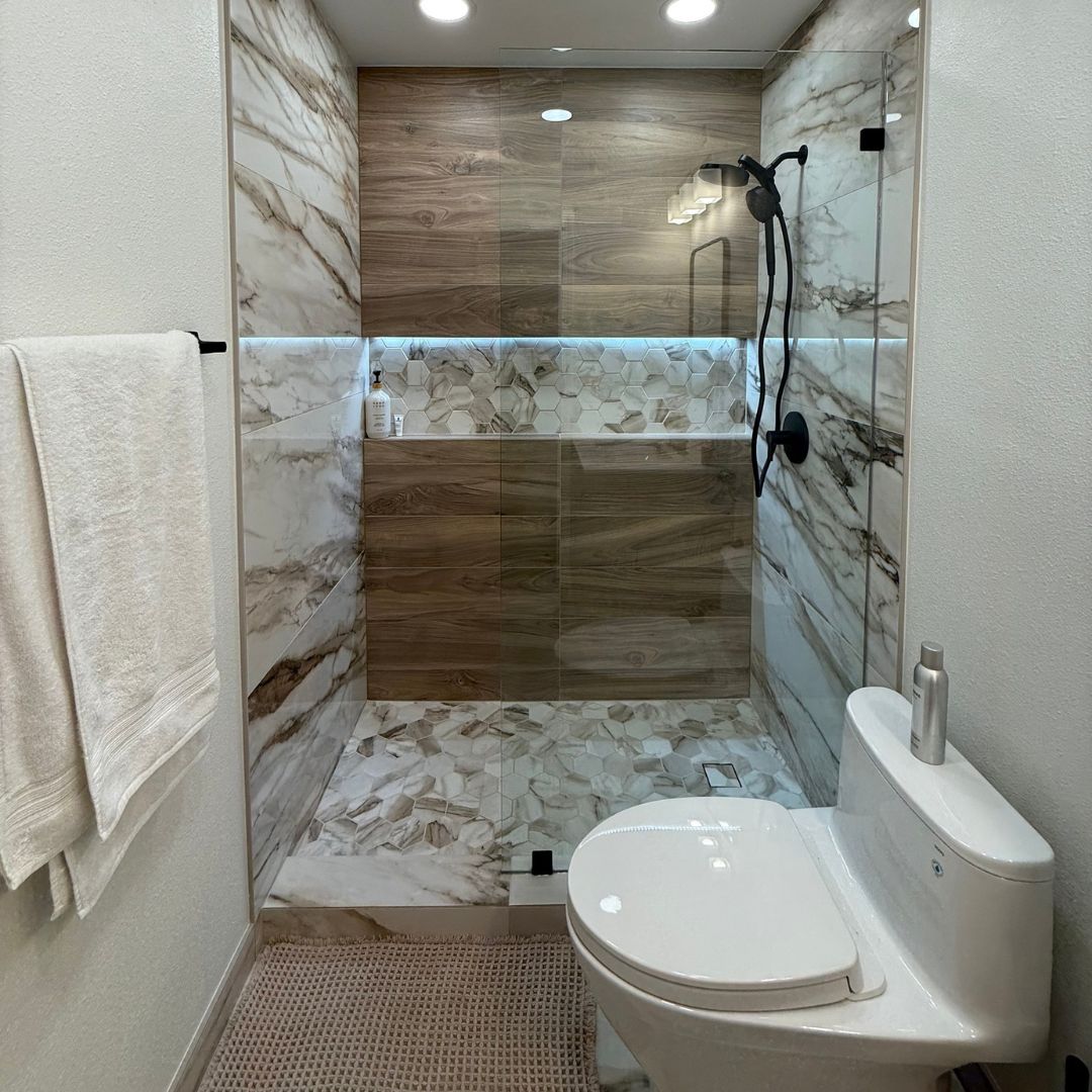 Walk-in shower renovation with large-format tile walls, glass enclosure, and modern fixtures