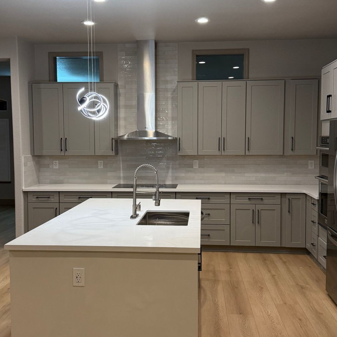 Modern kitchen remodel with gray shaker cabinets, large white island, and recessed lighting