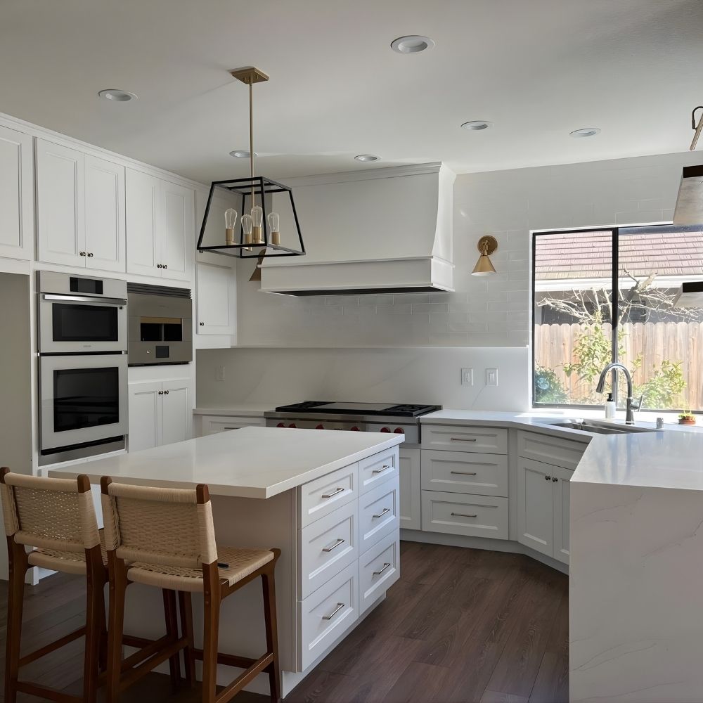 Bright white kitchen remodel with double wall ovens, waterfall island, and bar seating