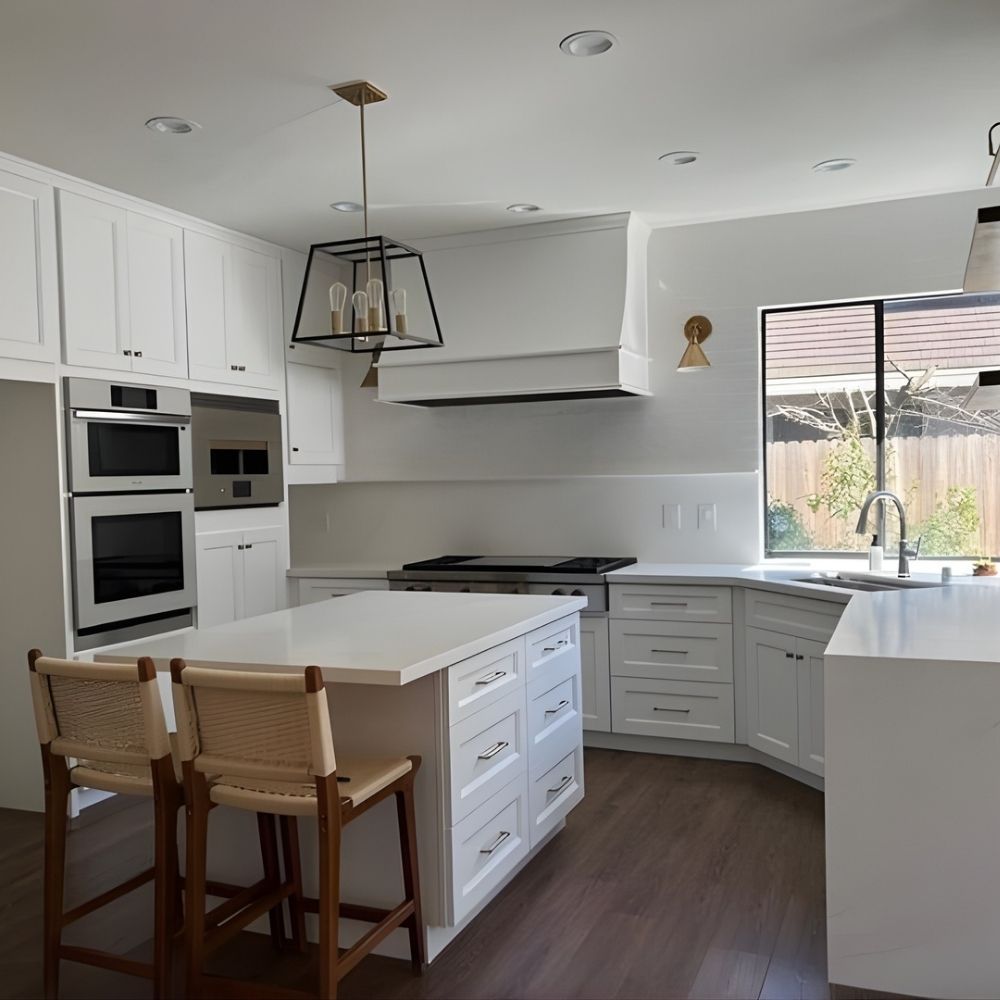 Bright kitchen with custom cabinetry, waterfall island, double ovens, and bar seating