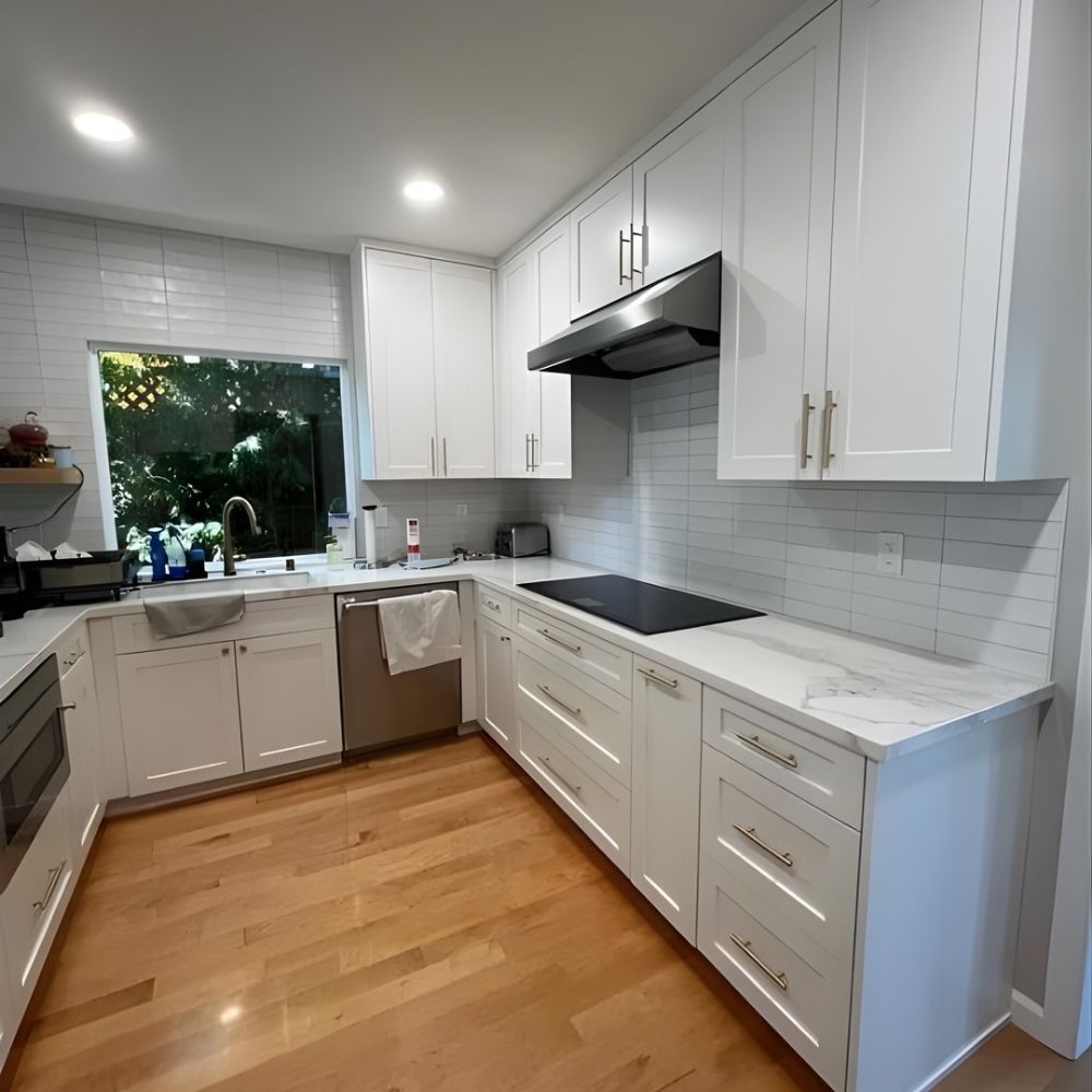Sleek kitchen upgrade featuring long countertops, white shaker cabinets, and natural light