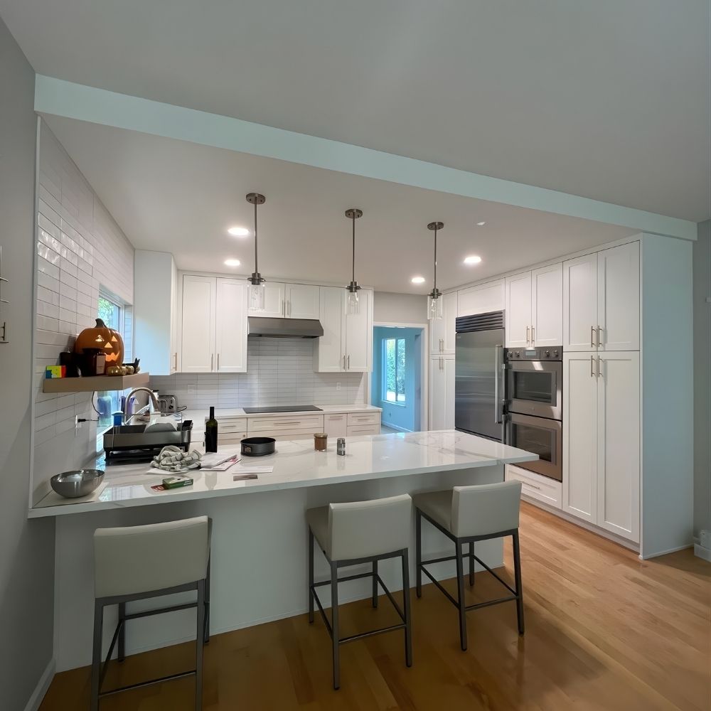 Spacious kitchen island with seating, custom cabinets, quartz counters, and pendant lights