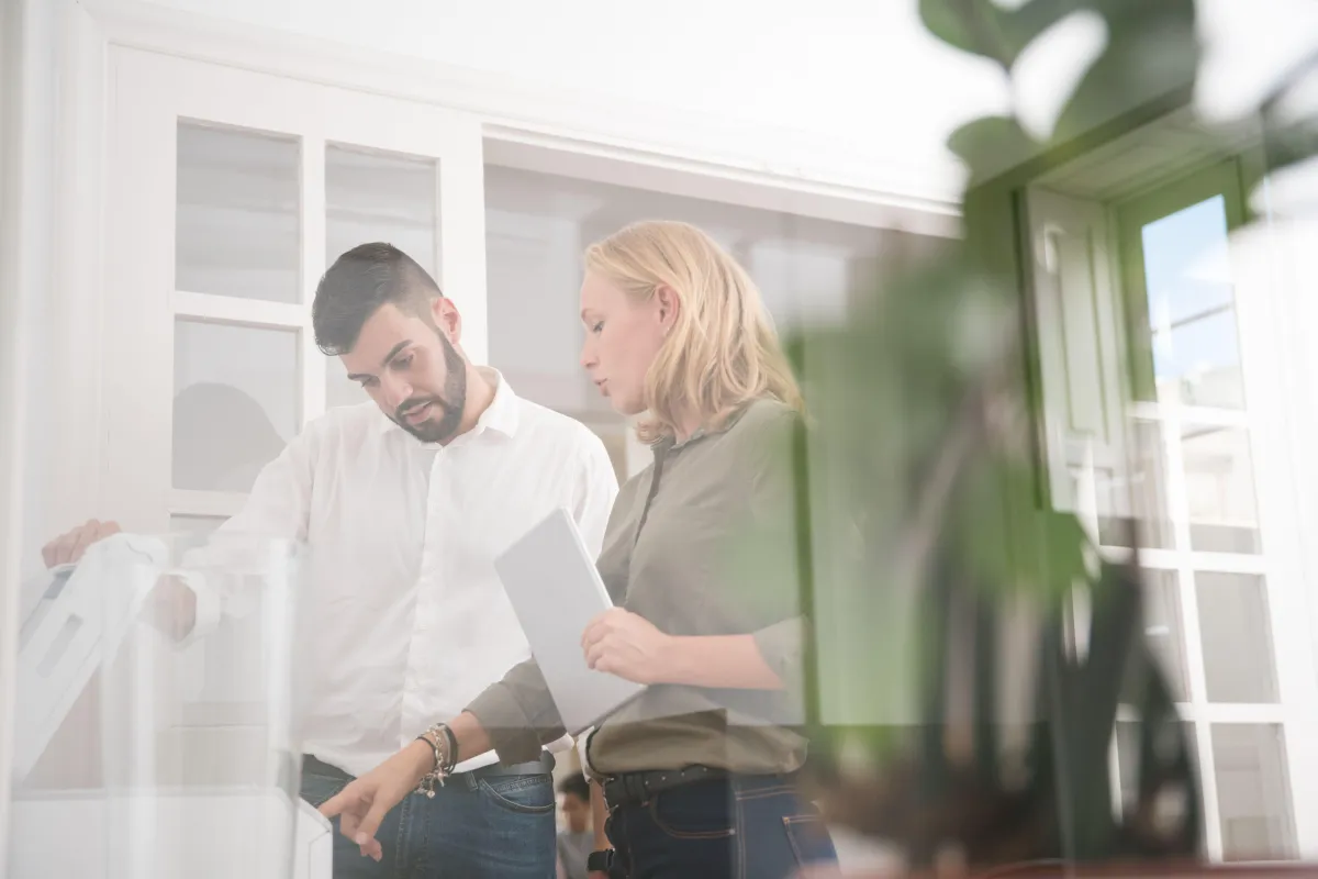 Two colleagues standing in a bright office discussing a printed document