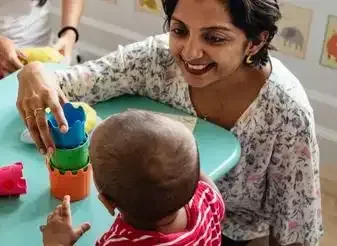 A teacher and child playing with blocks at a Sydney childcare centre supported by the Unlimited Print Plan.