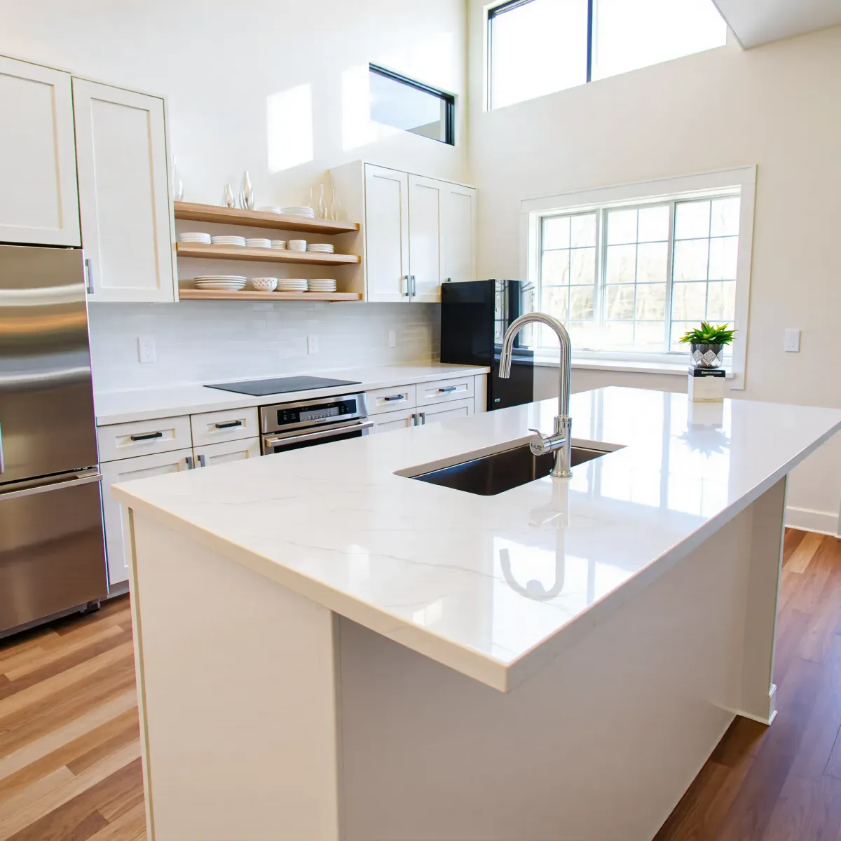 Modern Knoxville kitchen with sleek quartz countertop, stainless steel appliances, glass faucet, light cabinetry, and abundant natural light.