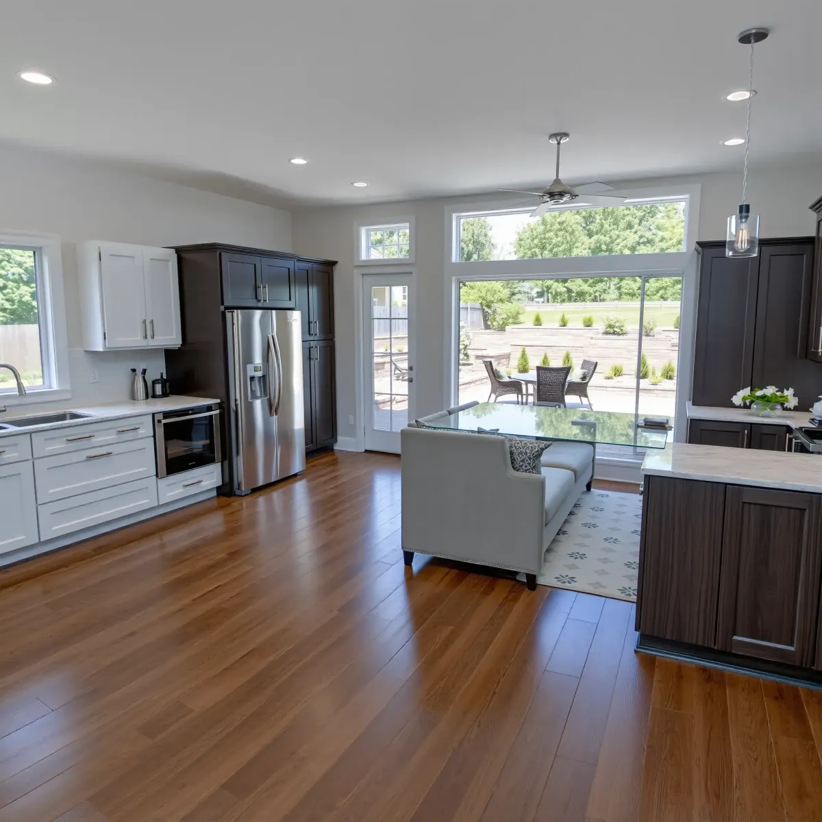 Modern living room in Seymour, TN with hardwood floors, custom cabinetry, large windows, and an open-concept kitchen.
