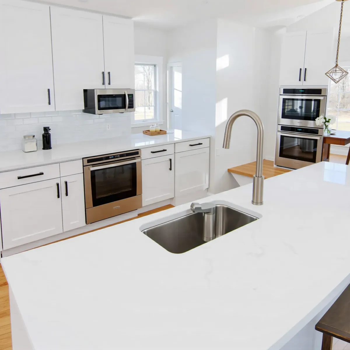 Modern Rockford, TN kitchen with sleek matte cabinets, granite island, stainless steel appliances, hardwood floors, and greenery views.